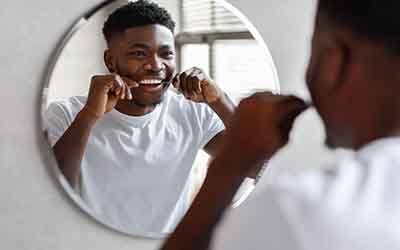 a person flossing his teeth in a mirror