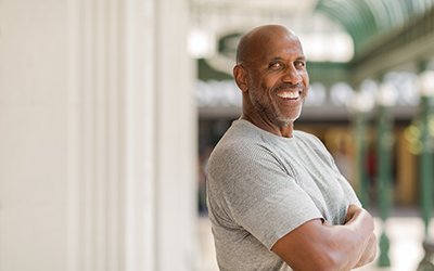 Man in gray shirt smiling outside