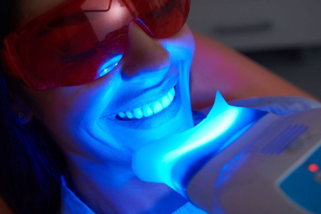 A woman getting a professional teeth whitening treatment at her dentist's office.