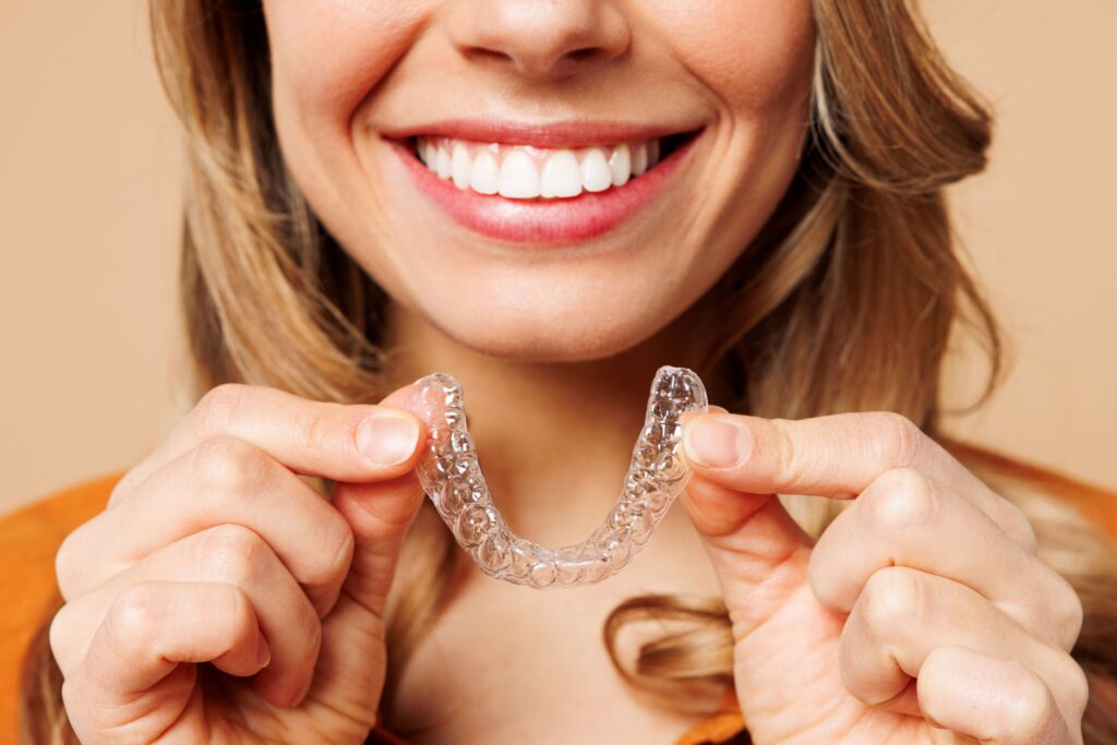 view of woman smiling holding Invisalign below chin